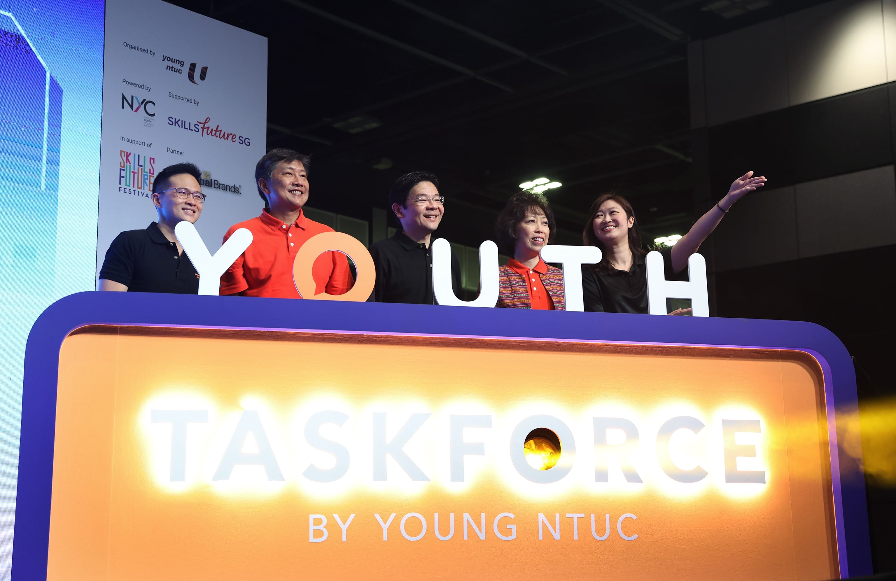 Five people stand behind "YOUTH" letters atop "TASKFORCE BY YOUNG NTUC" signage.